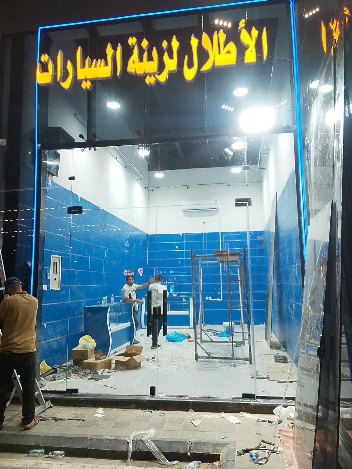 واجهة محل بزجاج سكريت مع إطار مضاء ولوحة محل مركّبة ليلاً
